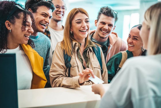 Group of young people takes room key card at check in of youth h